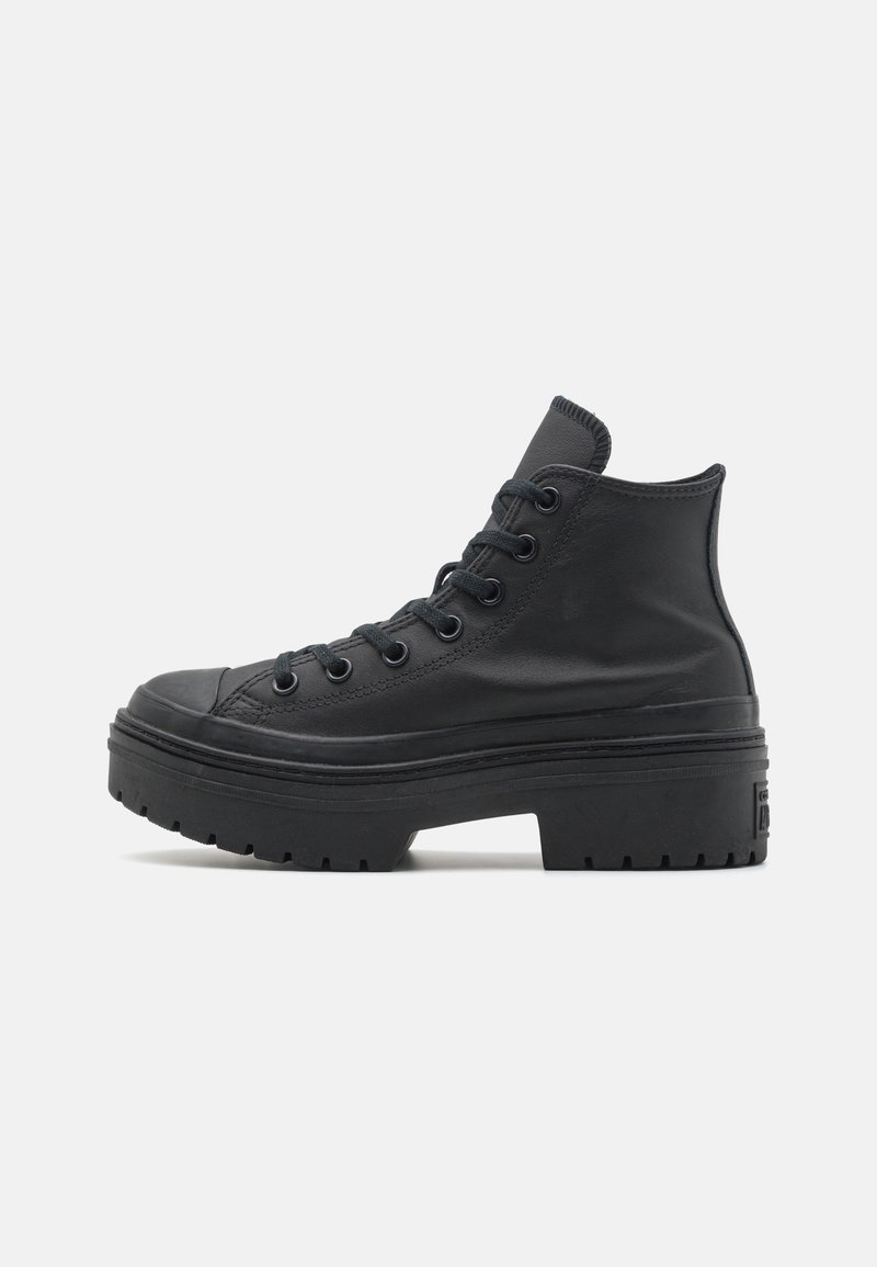 Botte montante en cuir noir avec semelle épaisse, laçage à l'avant et semelle texturée, vue de profil sur un fond uni.