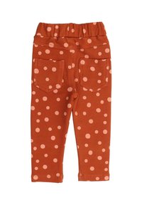 Orange leggings with a polka dot pattern in light pink, featuring an elastic waistband and two back pockets. Smooth, stretchy fabric.