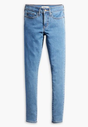 Jeans ajustados de denim azul claro. Presentan un diseño de cinco bolsillos con costuras contrastantes y un cierre de cremallera con un botón de metal.