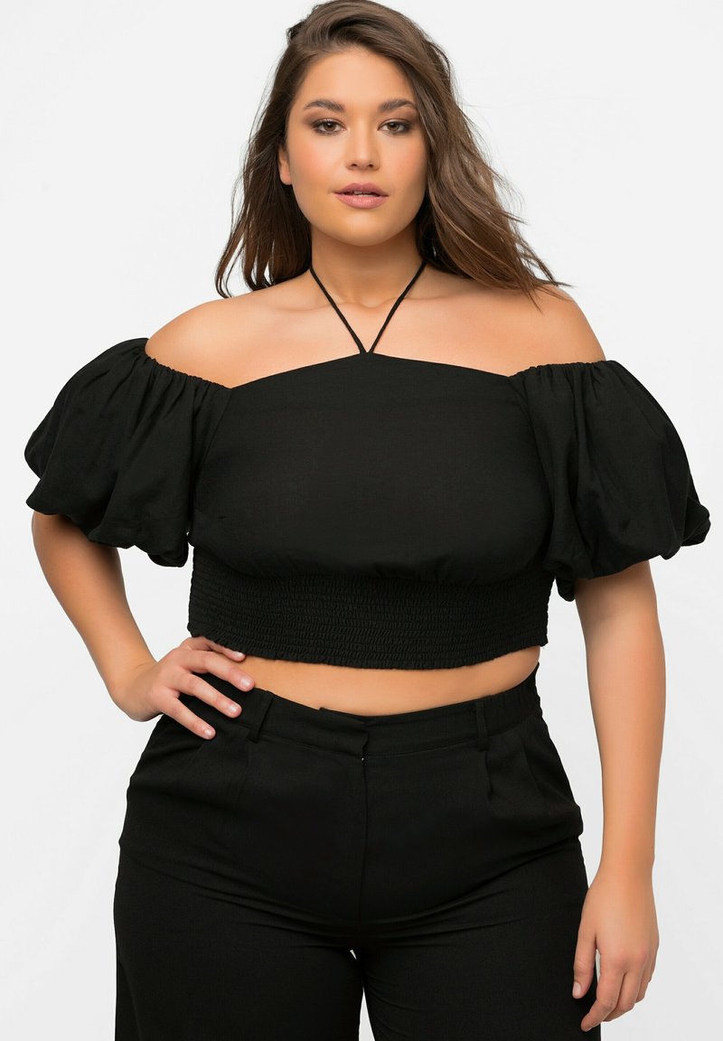Sort off-shoulder cropped top med puffærmer, smocket talje og tynd halsrem. Bæres med højtaljede sorte bukser.