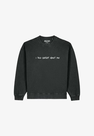 Musternäe musta sviitri, millel on ümmargune kaelus ja langenud õlad. Esifoonil keskel valgest tekstist graafika "RÄÄKISIN CHATGPT-S RINGI SINUST".