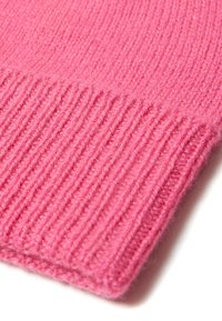 Tissu tricoté rose vif avec une texture côtelée et un bord plié net. Matériau doux suggérant chaleur et confort.