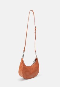 Petit sac bandoulière en cuir embossé crocodile orange-brun avec fermeture éclair argentée et bandoulière longue réglable, marque Steve Madden.