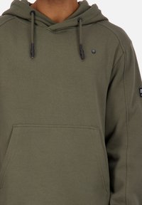 Olijfgroene hoodie van zachte stof, met een voorzak, verstelbare trekkoorden en een klein logo-detail op de borst.