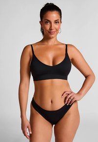 Zwarte tweedelige badpak bestaande uit een bralet-top met dunne bandjes en een bikinibroekje met lage taille, gemaakt van glad, rekbaar materiaal.