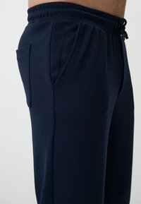 Marineblaue Jogginghosen aus weichem Material, mit elastischem Bund, Kordelzug und einer Seitentasche für Stauraum.