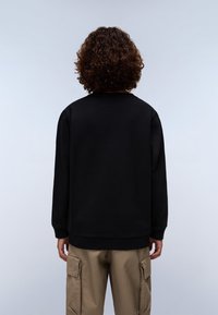 Felpa nera con collo rotondo e maniche lunghe, abbinata a pantaloni cargo beige, caratterizzati da una trama liscia e una vestibilità rilassata.