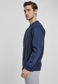 Marineblå sweatshirt med rund hals, ribbestrikkede mansjetter og linning. Laget av et strukturert stoff, med et enkelt design uten mønstre.