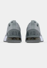 Pair of gray athletic shoes shown from the back, featuring thick soles with visible air cushioning and fabric pull tabs on the heels.