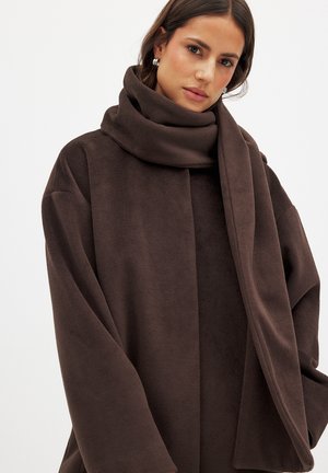 Brown fleece coat with a wide, draped design and oversized sleeves. Features a matching scarf, soft texture, and minimal seams.