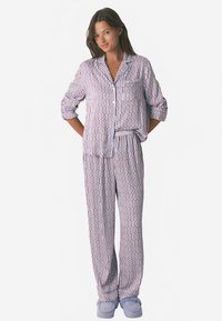 Ensemble de pyjama en coton avec un motif géométrique en violet, rose et blanc. Chemise à manches longues avec boutonnière sur le devant et pantalon assorti.
