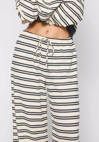 Pantalones de lounge a rayas en crema y azul marino, con un tejido texturizado, diseño de pierna ancha y una cintura con cordón ajustable.