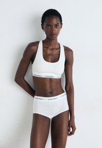 Weißes Calvin Klein Sport-BH- und Unterwäsche-Set, gefertigt aus glattem Baumwollmaterial mit einem weichen Stretch. Verfügt über ein Logo-Band und minimalistisches Design.