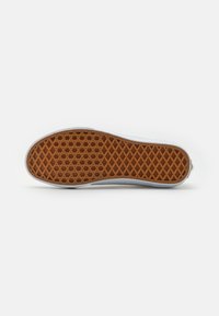 Suela de zapato de goma con un agarre de patrón hexagonal en marrón, bordeada por un borde blanco. Textura suave con un perfil plano.