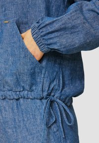 Denim top met elastische manchetten en tailleband. Heeft een voorzak en trekkoorddetails. Levendige blauwe kleur en gestructureerde stof.