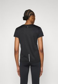 Melna sporta T-krekls ar īsām piedurknēm, apaļu kakla izgriezumu un baltu vertikālu akcentu aizmugurē, izgatavots no gludas, vieglas auduma.