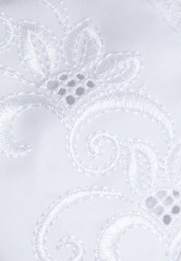 Tissu blanc présentant une broderie complexe avec des motifs floraux, une texture en relief et de petits accents découpés, améliorant les détails visuels.