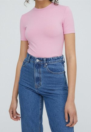 Maglietta a maniche corte rosa chiaro a coste abbinata a jeans in denim blu a vita alta, con vestibilità classica e dettaglio con bottone in vita.