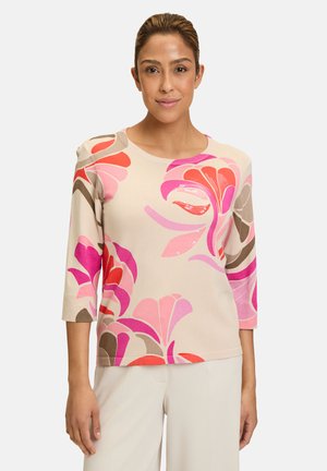 Beige top met bloemenpatroon en lange mouwen, voorzien van levendige roze, rode en bruine designs. Ronde halslijn en getailleerde stijl.