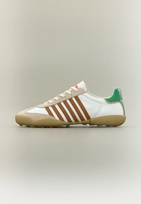 Λευκό αθλητικό παπούτσι με καφέ ρίγες, μπεζ κομμάτια από σουέντ, καουτσούκ σόλα και πράσινη ετικέτα στη φτέρνα, εμφανίζεται από το πλάι σε ουδέτερο φόντο.