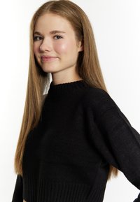 Maglione nero lavorato a maglia con colletto e orlo a coste, caratterizzato da maniche lunghe, leggermente oversize, e una finitura testurizzata.