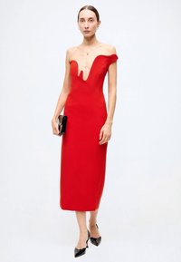 Red, fitted midi dress with off-the-shoulder design and plunging neckline. Smooth fabric, simple silhouette, paired with a black clutch.