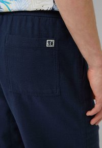 Navy blue, strukturalne szorty z elastycznym paskiem w talii, z tylną kieszenią i małą metką z logo na kieszeni.