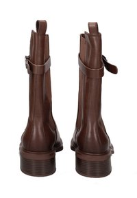 Bottines en cuir marron avec des panneaux élastiques sur les côtés, des accents de boucle et un talon empilé texturé. Le design est structuré et élégant.