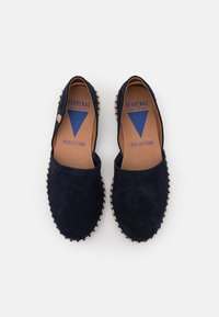 Navy suede slip-on espadrilles with a woven beige sole. Features a blue triangle logo and natural leather insole, designed for comfort.