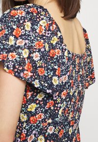 Vestido floral con fondo azul marino oscuro, flores multicolores brillantes, mangas cortas abullonadas y un cuerpo fruncido con escote cuadrado.