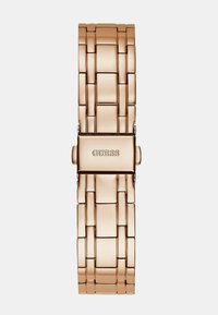 Kovinska ura v rožnato zlato, z zasnovo povezave in pravokotnimi akcenti. Sponka prikazuje graviran logotip "GUESS". Gladek, sijoč zaključek.