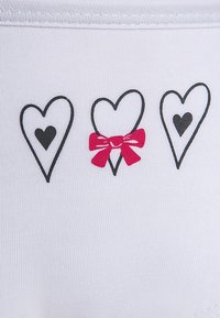 Bijela tkanina s tri ilustracije srca. Dva su obrubljena crnom bojom s ispunjenim crnim središtima, a srednje srce ima ružičastu mašnu kao naglasak.