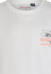 Biała bawełniana koszulka z okrągłym dekoltem, czarno-brzoskwiniowym kwiatowym wzorem oraz logo RETOUR JEANS. Lekka faktura.