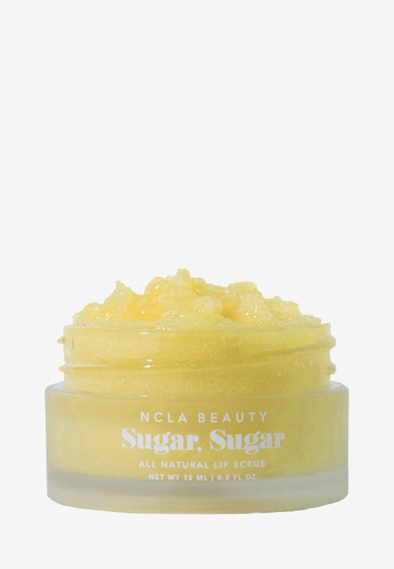 Gul kornete leppeskrubb i en liten frostet glasskrukke merket "NCLA Beauty Sugar, Sugar All Natural Lip Scrub 15 ml" mot en hvit bakgrunn.