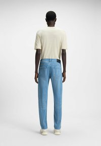 Jeans azzurri chiari con una vestibilità rilassata, realizzati in denim, caratterizzati da un classico design a cinque tasche e un'etichetta nera sulla cintura posteriore.