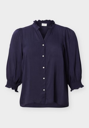 Bluză albastru închis cu guler și manșete cu volane, închidere frontală cu nasturi și mâneci bufante trei-sferturi.