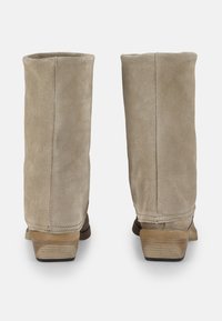 Botines de ante beige con una textura suave, forma cuadrada y tacón apilado. Presentan un diseño sencillo y detalles de costura mínimos.