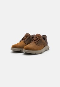 Braune Lederschuhe mit runden Zehen, braunen Schnürsenkeln und einer gepolsterten grauen Sohle. Texturiertes Design am Fersenbereich.