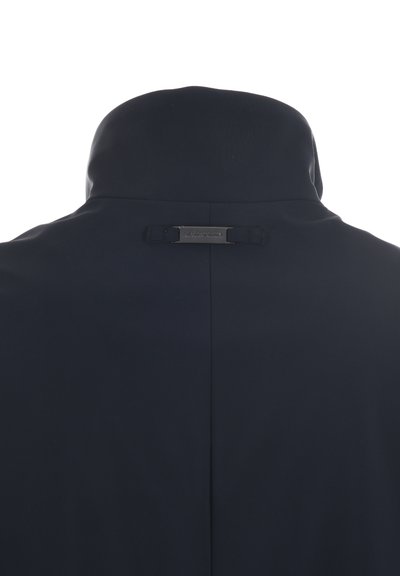 Marineblauwe jas met hoge kraag en een gladde textuur. Heeft een klein metalen label dat aan de achterkant is genaaid en een slanke silhouet.