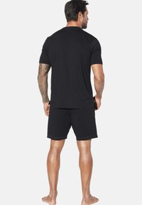 Black cotton short-sleeve t-shirt and shorts set, featuring a simple design with visible stitching details and a relaxed fit.