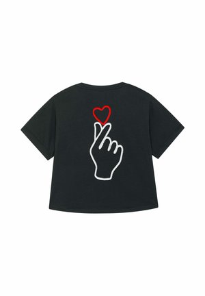 Black t-shirt featuring a white outline of a hand making a heart gesture, with a red heart above the fingertips. Simple and contemporary design.