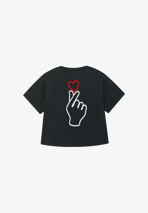 Schwarzes T-Shirt mit einer weißen Kontur einer Hand, die eine Herzgeste macht, und einem roten Herzen über den Fingerspitzen. Schlichtes und zeitgemäßes Design.