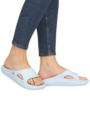 Light blue slide sandals made of soft material, featuring cut-out design, cushioned sole, and a subtle brand logo on the side.