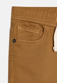 Bruine stoffen broeken met een klein voorvak, textuurstof en contrasterende stiksels, met een crèmekleurige koord in de taille.