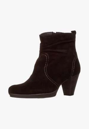 Stivaletto in suede nero con design morbido, dettagli di cucitura bianca e tacco impilato. Presenta una punta rotonda e una superficie texturizzata.