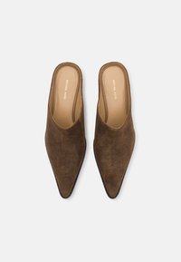 Brune semskede mules med spidse tæer og åbne bagdele, der har et elegant design og minimal branding på indersålerne.