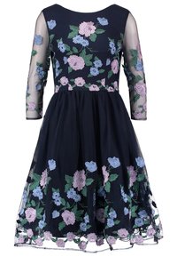 Marineblauwe jurk met driekwart doorzichtige mouwen, versierd met bloemenborduurwerk in roze, blauw en groen. Vloeiende rok met kant aan de zoom.