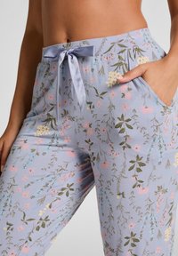 Bloemige pyjamabroek in lichtlavendel met een trekkoord in de taille, versierd met een mix van roze, blauwe en groene botanische patronen. Inclusief zijzakken.