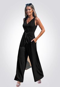 Mono negro con cinturilla ajustable, diseño sin mangas, piernas anchas y bolsillos. Tejido de punto con un acabado texturizado.