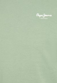 Světlé zelené tričko s hladkou texturou, s bílým logem "Pepe Jeans London" umístěným vlevo nahoře.